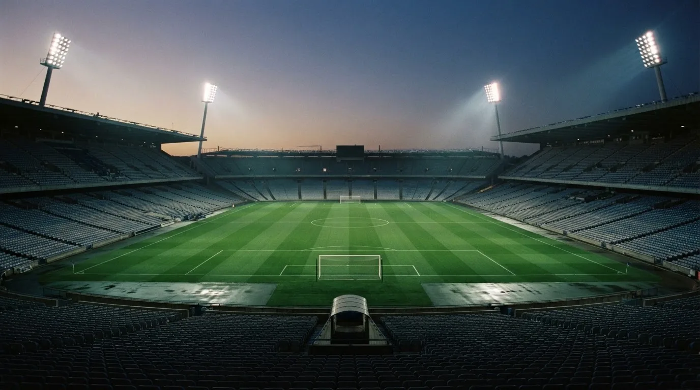 Een leeg voetbalstadion met lichtmasten bij schemering