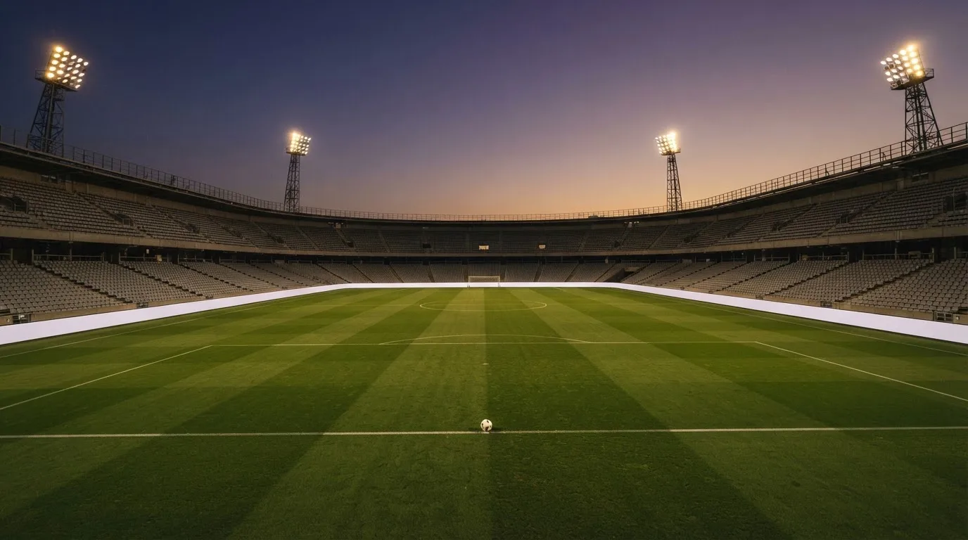 Een leeg voetbalstadion met lichtmasten bij schemering