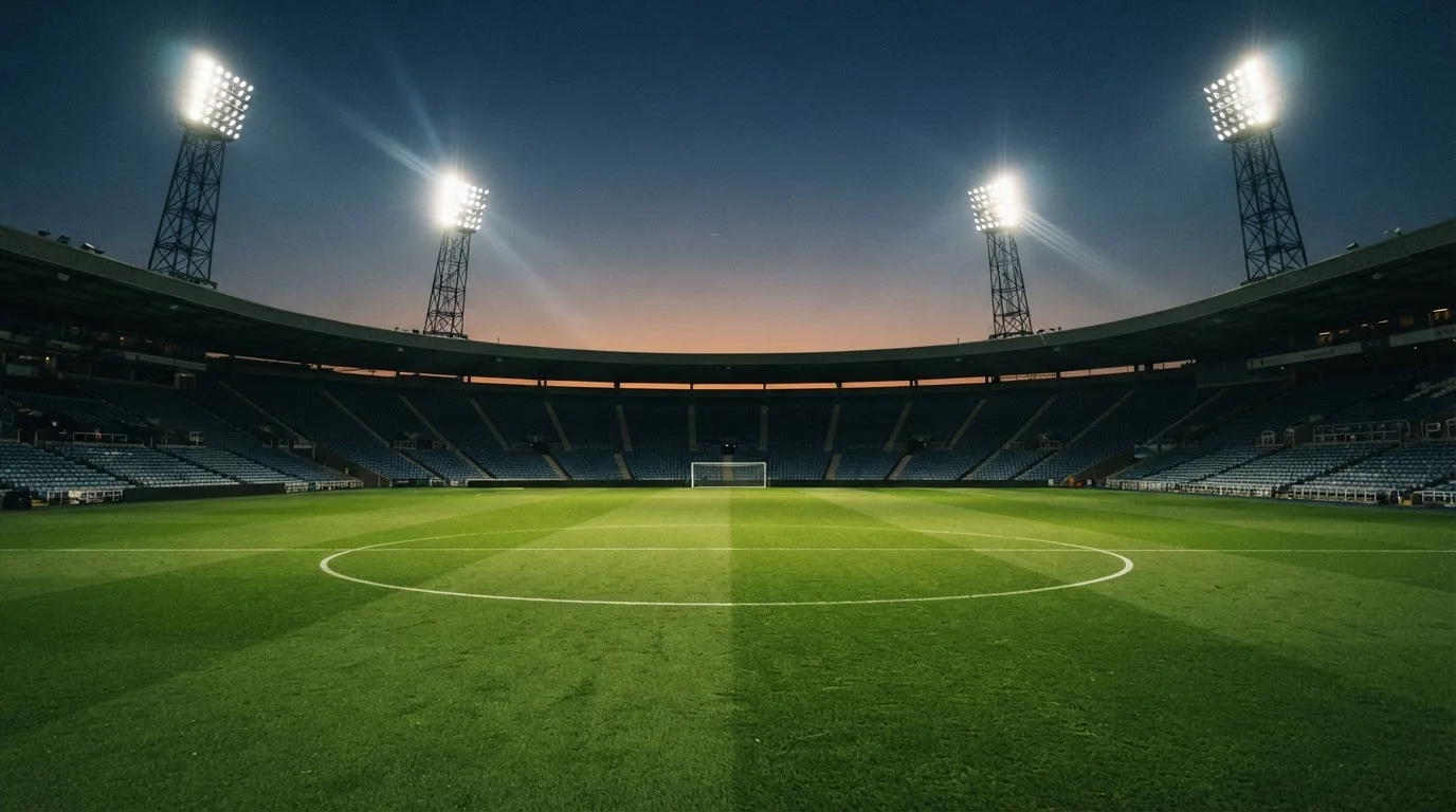 Een leeg voetbalstadion met lichtmasten bij schemering