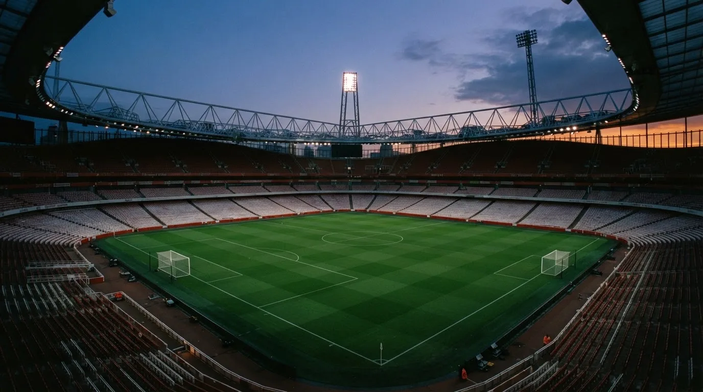 Een leeg voetbalstadion met lichtmasten bij schemering