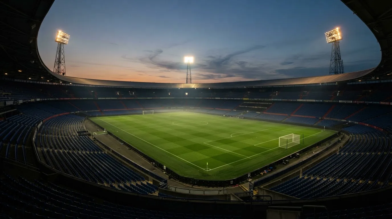 Een leeg voetbalstadion met lichtmasten bij schemering