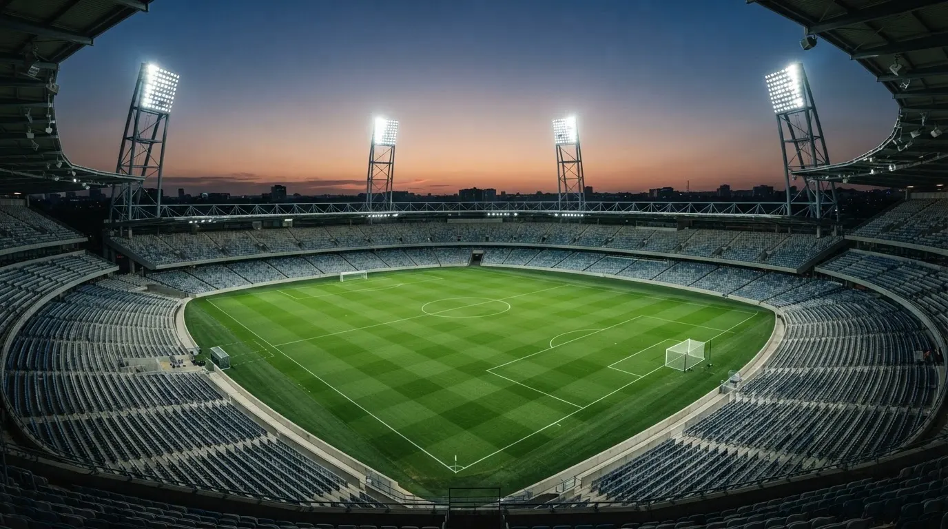 Een leeg voetbalstadion met lichtmasten bij schemering