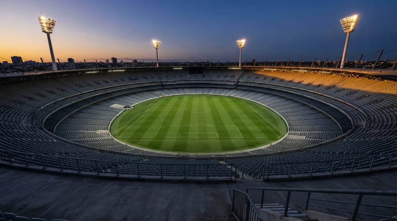 Een leeg voetbalstadion met lichtmasten bij schemering