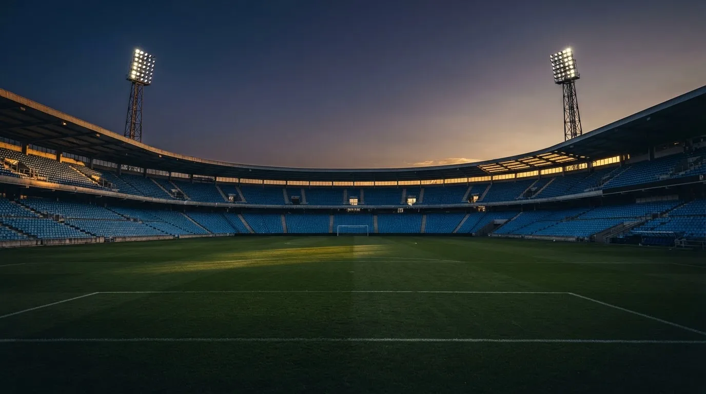 Een leeg voetbalstadion met lichtmasten bij schemering