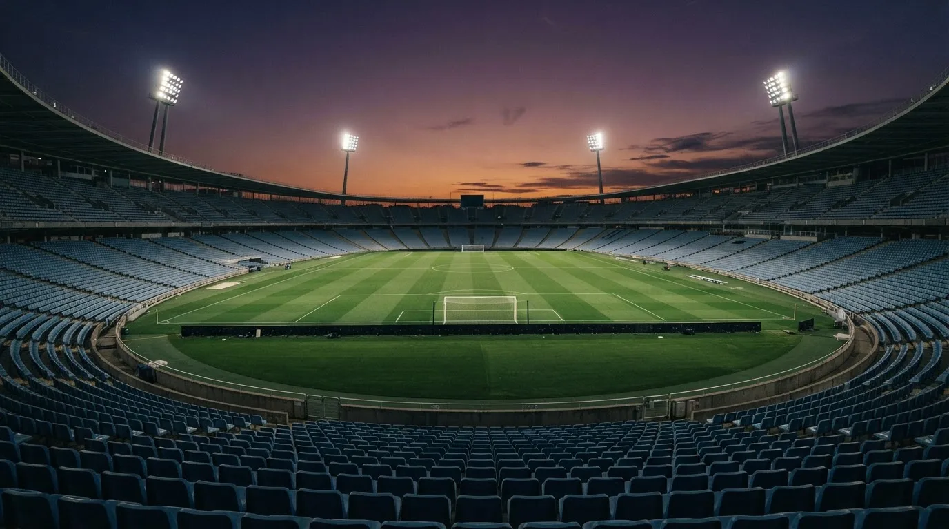 Een leeg voetbalstadion met lichtmasten bij schemering