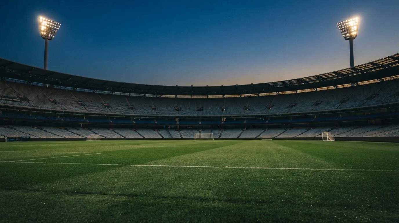 Een leeg voetbalstadion met lichtmasten bij schemering