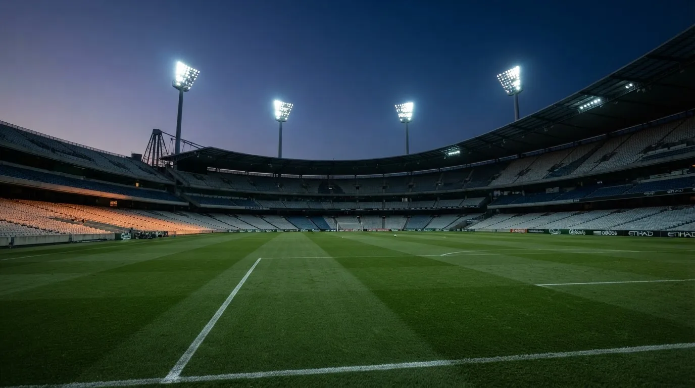 Een leeg voetbalstadion met lichtmasten bij schemering