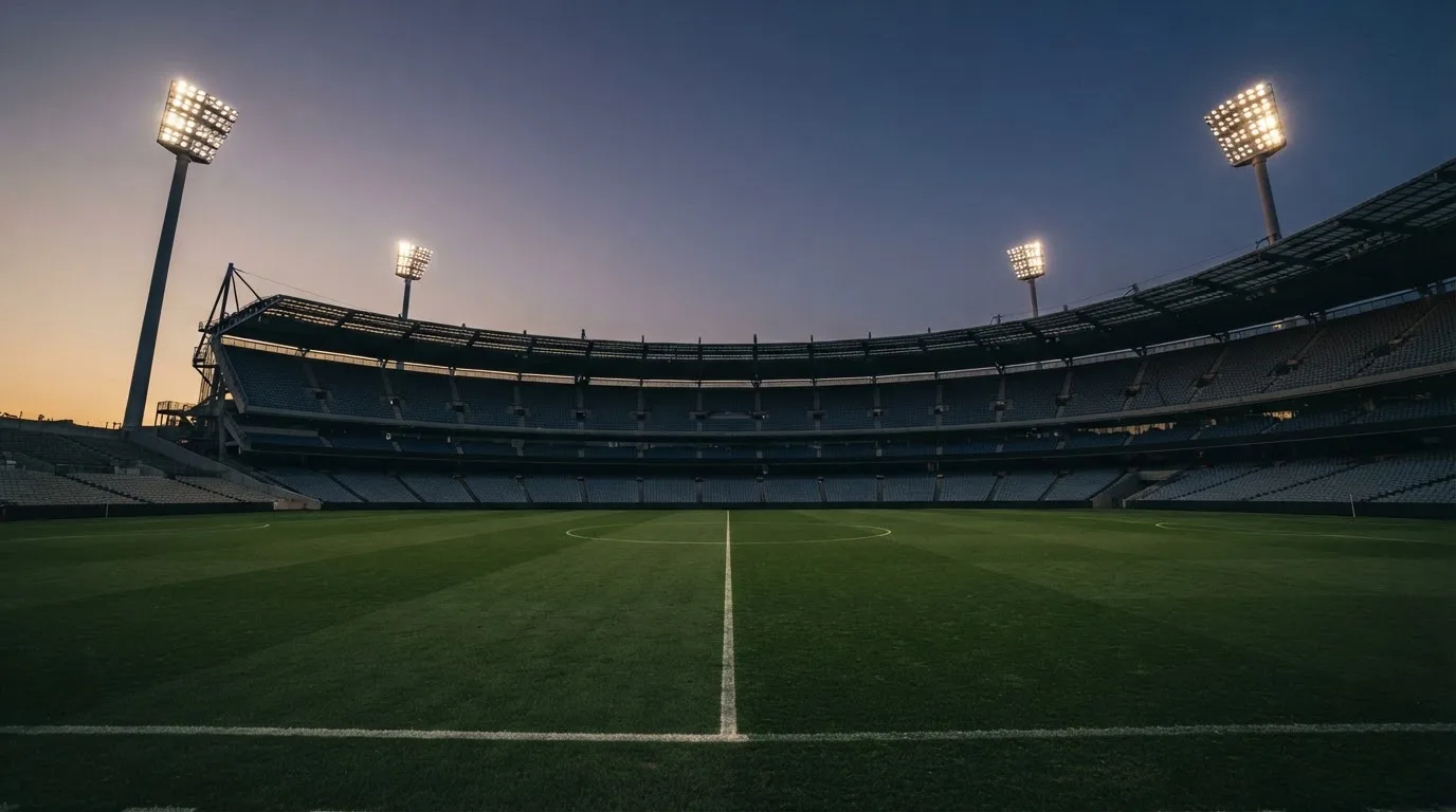 Een leeg voetbalstadion met lichtmasten bij schemering