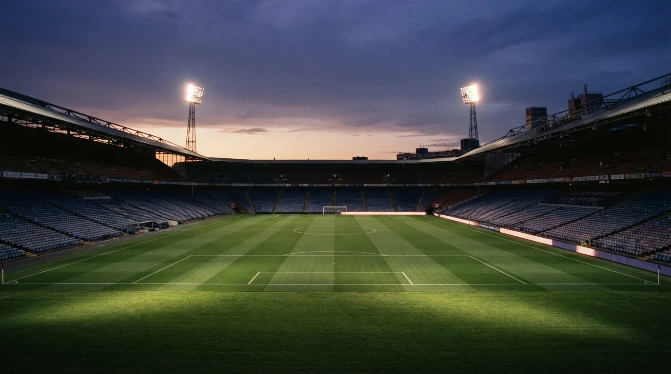 Een leeg voetbalstadion met lichtmasten bij schemering