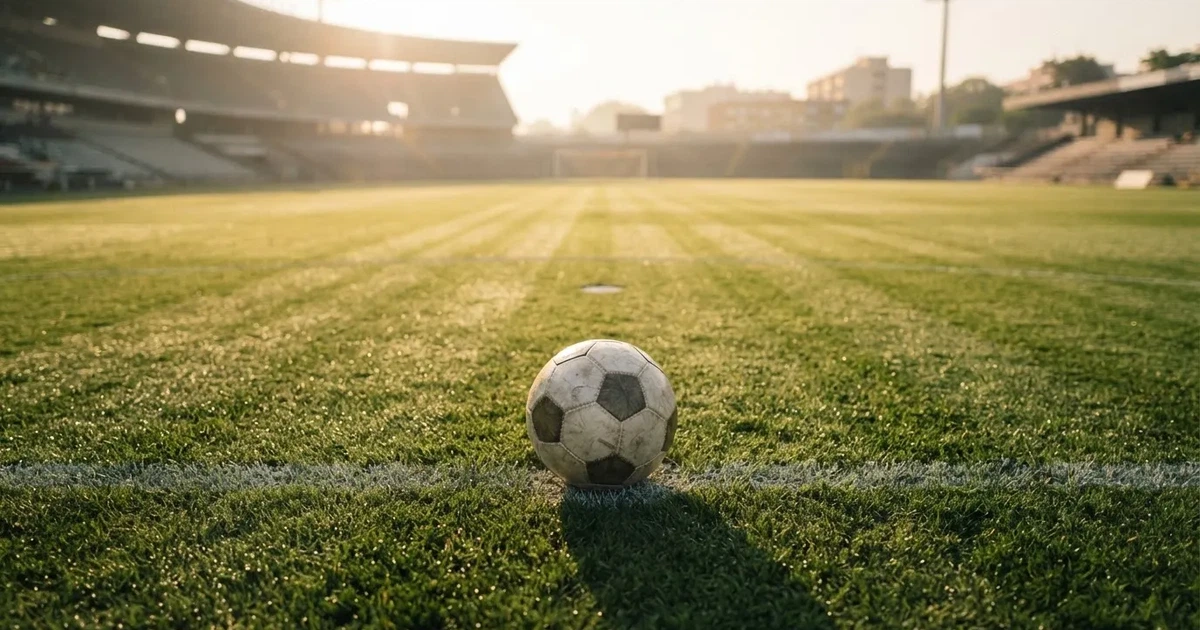 Een voetbal op de middenstip van een grasveld in het ochtendlicht